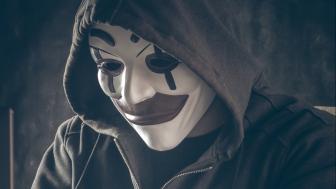 Cybercrimineel met masker achter de laptop